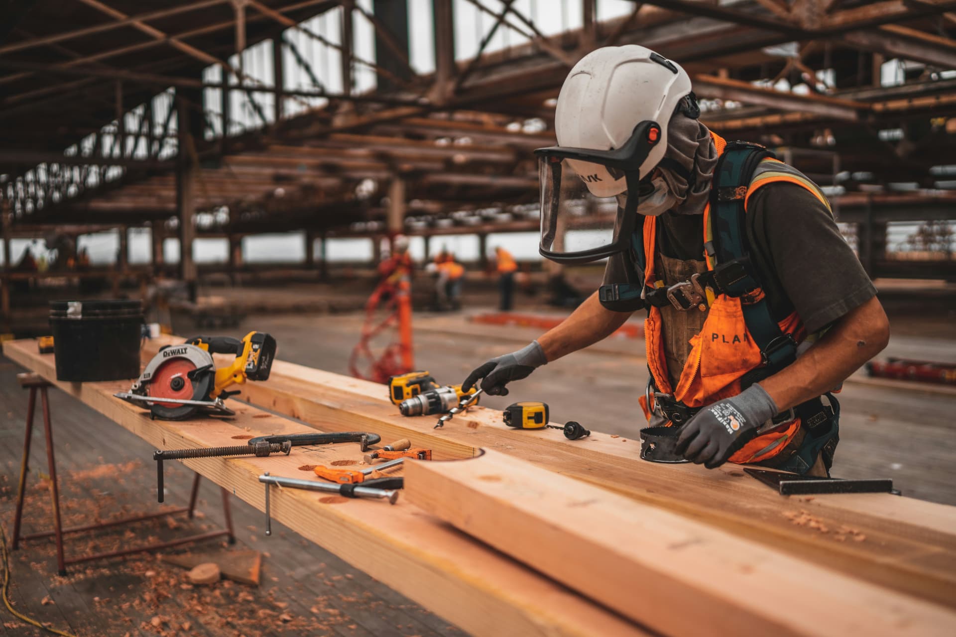 A self-employed carpenter drilling a timber beam on site