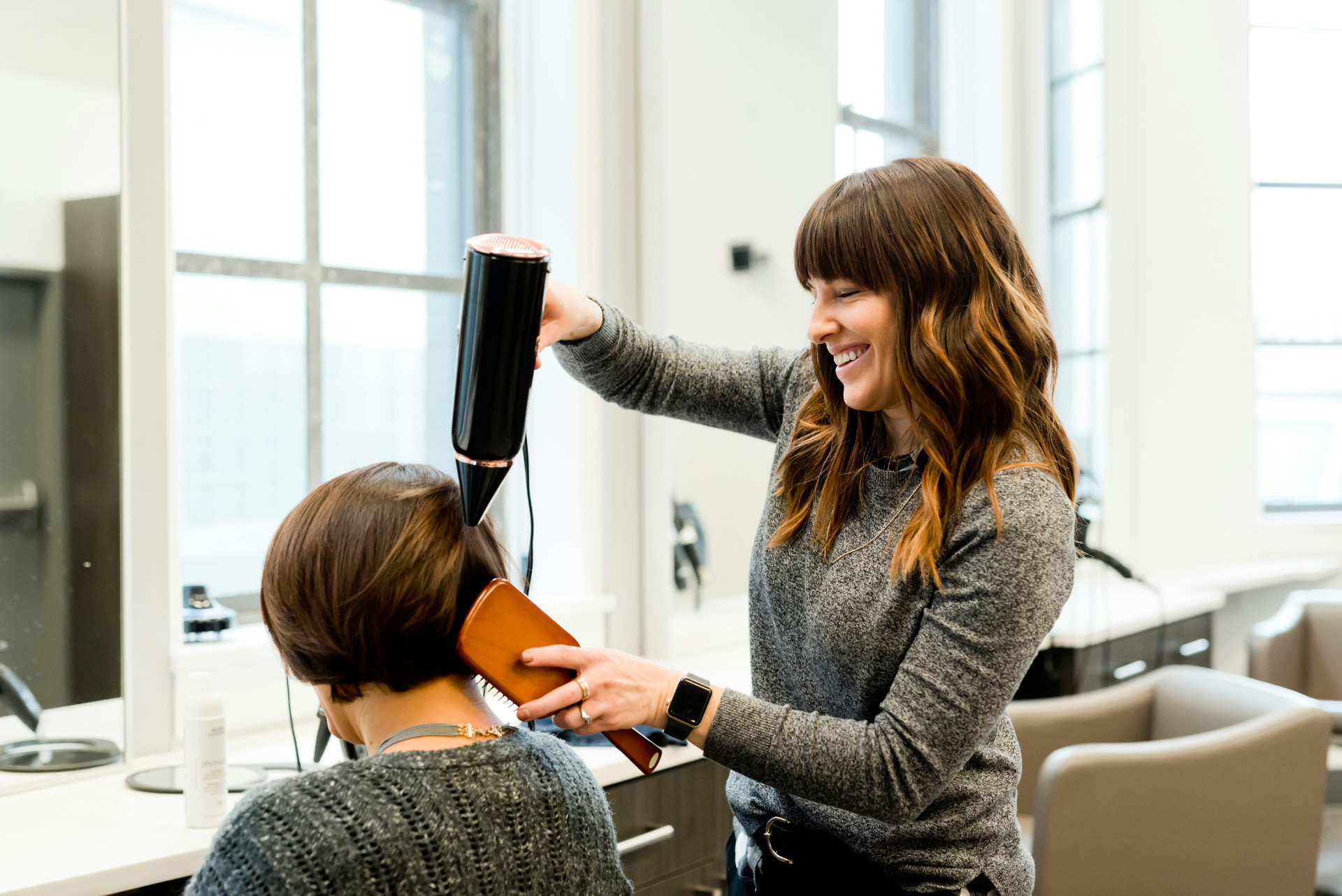 A self-employed hairdresser blow-drying a client's hair in her salon